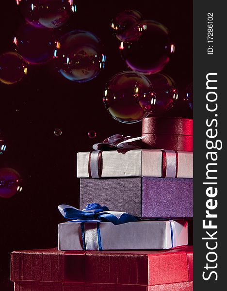 Stack of gifts and bubbles floating in the air. shooted in studi on a black background