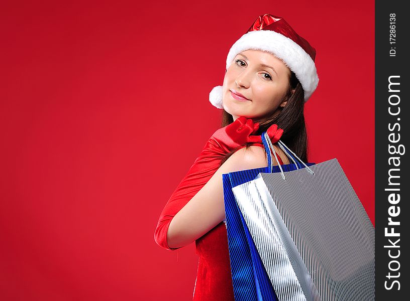 Portrait of a young charming girl dressed as Santa with a bag of shopping in their hands. Happy New Year!