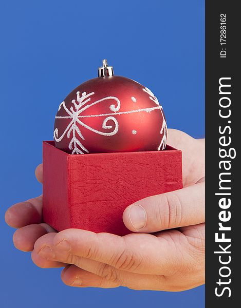 Red box with a christmass decorative ball holded in palms. Red box with a christmass decorative ball holded in palms