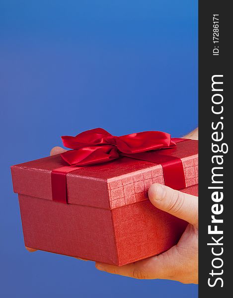 Red gift box holded with hand. shooted in studio on a blue background