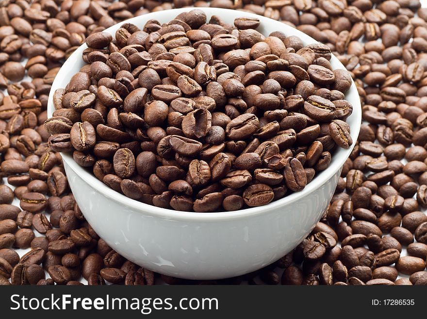 Close up of Coffee beans in and around a white bowl. Close up of Coffee beans in and around a white bowl