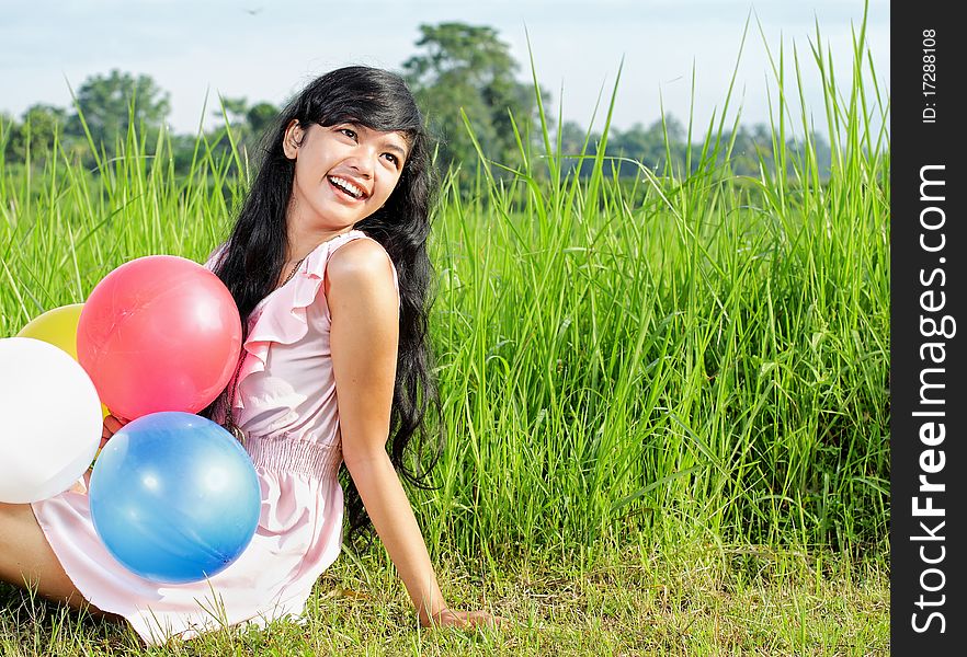 Beautiful teenage girl holding a bunch of colorful balloons in green nature. Beautiful teenage girl holding a bunch of colorful balloons in green nature
