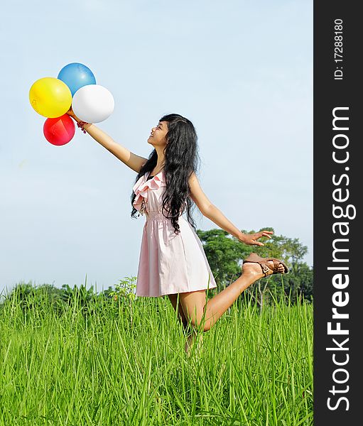 Young girl holding a bunch of colorful balloons in green nature. Young girl holding a bunch of colorful balloons in green nature