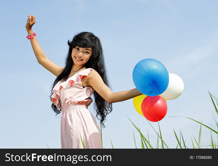 Young girl holding a bunch of colorful balloons in beautiful sky background. Young girl holding a bunch of colorful balloons in beautiful sky background