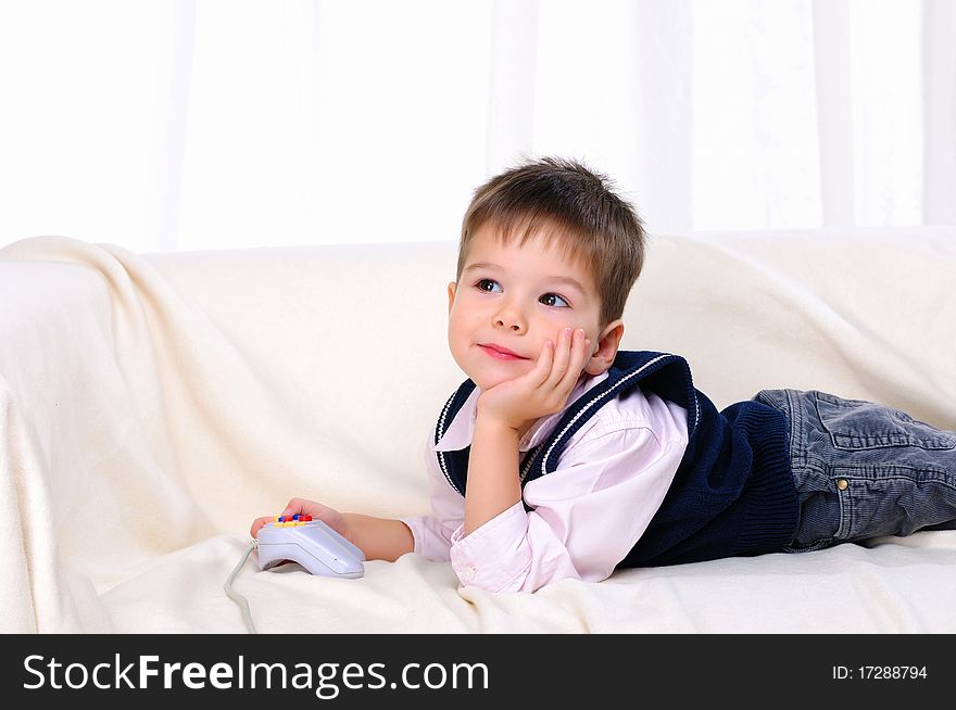 Little boy playing video games lying on the couch