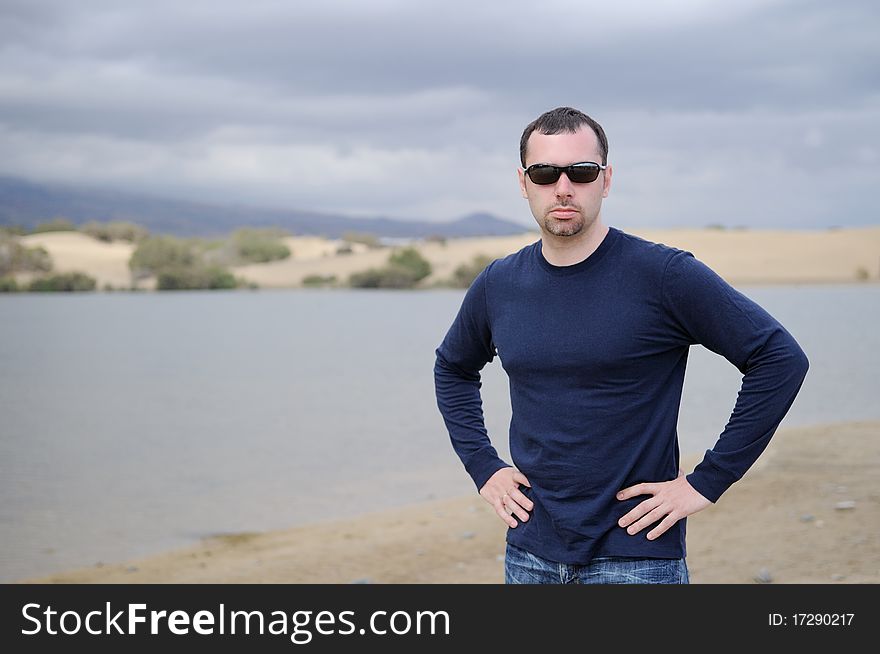 Young nice man in dark glasses on lake background before strom on Canary Island. Young nice man in dark glasses on lake background before strom on Canary Island