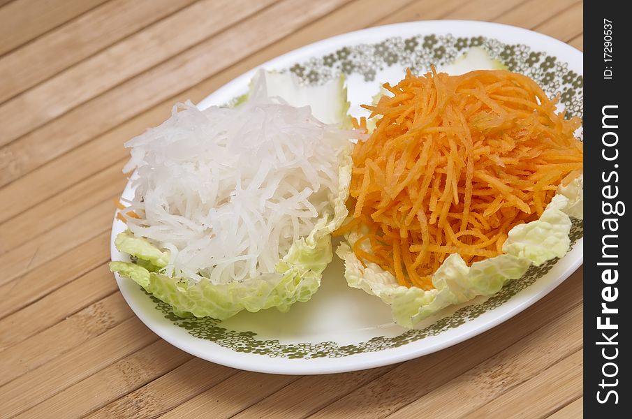 Fresh grated carrots and daikon radish on a piece of lettuce