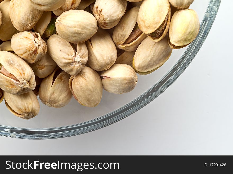 Pistachios nuts in glass bowl with white background