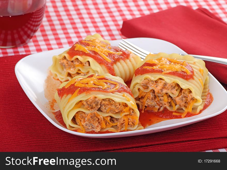 Lasagna noodles rolled up with sausage and topped with tomato sauce and cheese. Lasagna noodles rolled up with sausage and topped with tomato sauce and cheese