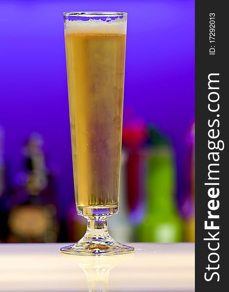 Beer glass on bar. Shallow depth of field, blurred alcohol bottles in background. Beer glass on bar. Shallow depth of field, blurred alcohol bottles in background.