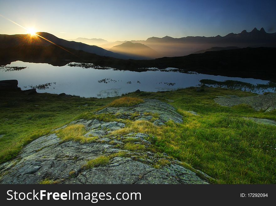 View over Guichard lake at sunrise in oisans near the famous col de la croix de fer, France. Aiguilles d'arve in the background. View over Guichard lake at sunrise in oisans near the famous col de la croix de fer, France. Aiguilles d'arve in the background.