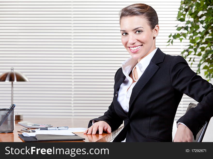 An attractive young woman happily works at her desk in her office. An attractive young woman happily works at her desk in her office