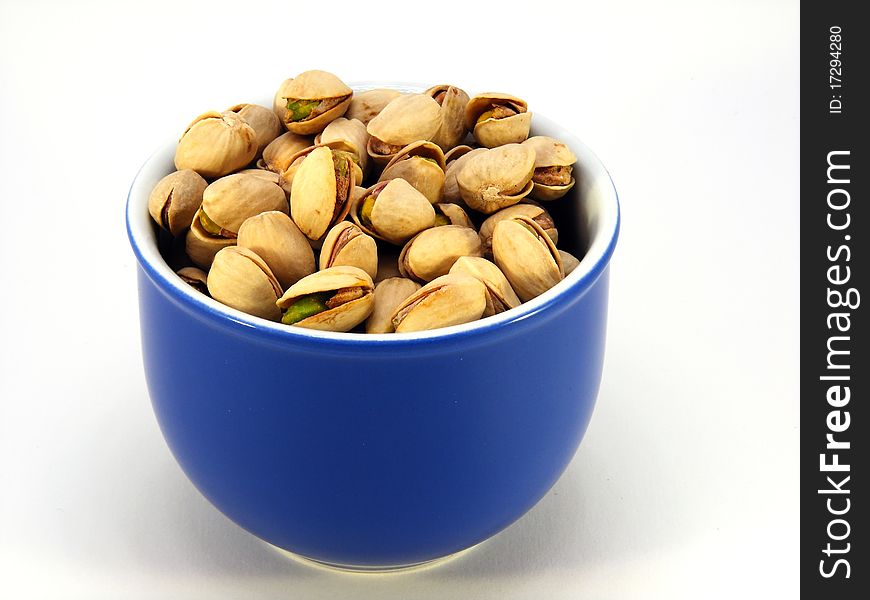 A blue bowl full of pistachio nuts. A blue bowl full of pistachio nuts