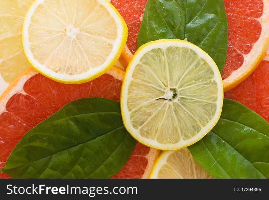 Fresh juicy grapefruits with green leafs close up