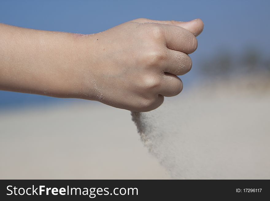 Small girl hand poring sand from her fist. Small girl hand poring sand from her fist