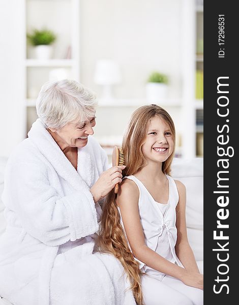 Grandmother granddaughter combs her hair at home. Grandmother granddaughter combs her hair at home