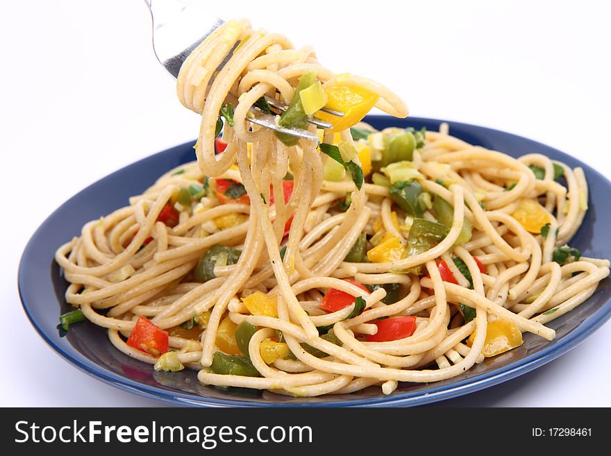 Spaghetti with vegetables being eaten with a fork on white background