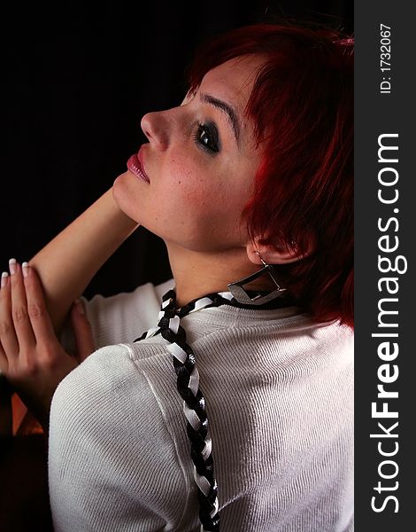 Sexy attitude of a young woman with red hair in soft light on black background