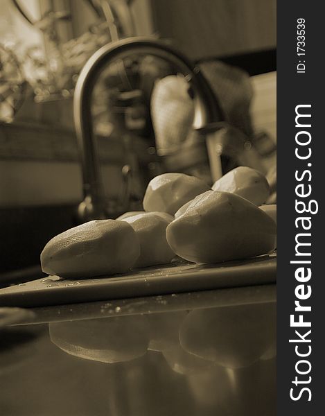 Peeled russet potatoes next to a kitchen sink shallow depth of field.  Potatoes are washed and ready for mashing. Peeled russet potatoes next to a kitchen sink shallow depth of field.  Potatoes are washed and ready for mashing.