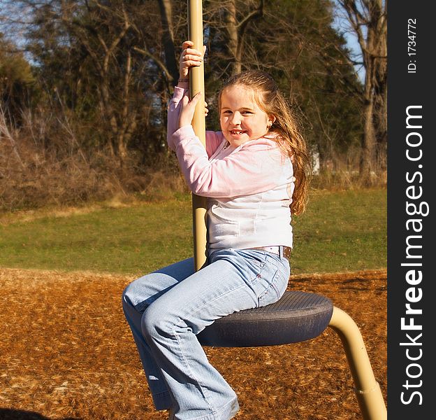 Happy girl on a pole swing at a playground. Happy girl on a pole swing at a playground