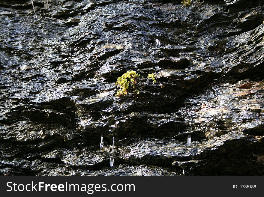 Mossy rocks on cliff with water running down