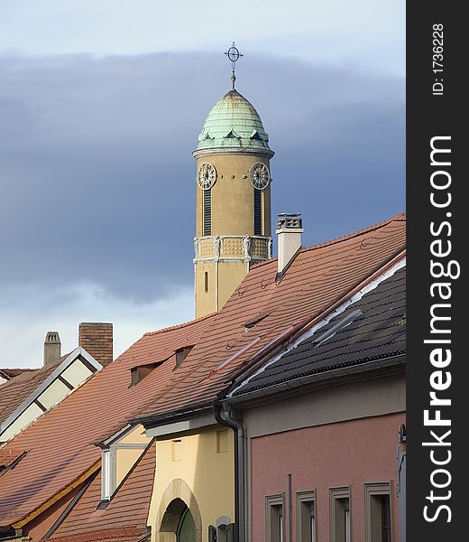 Church tower with a green rooftop behind a row of houses
