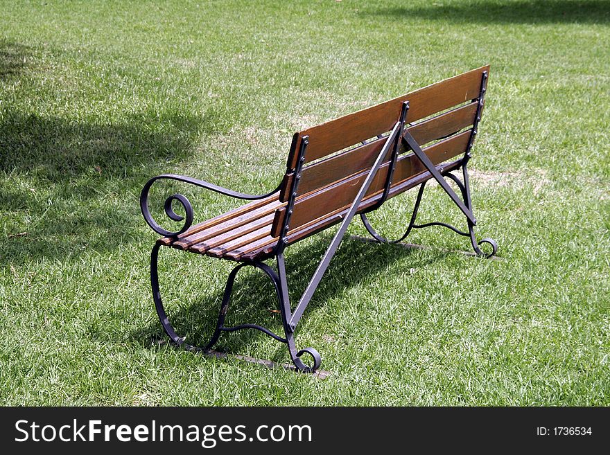 Backside Of An Empty Brown Park Bench With Metal Railing. Backside Of An Empty Brown Park Bench With Metal Railing