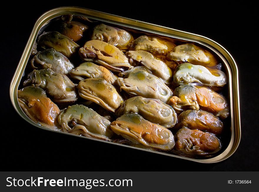 Smoked mussels in vegetable oil on a black background