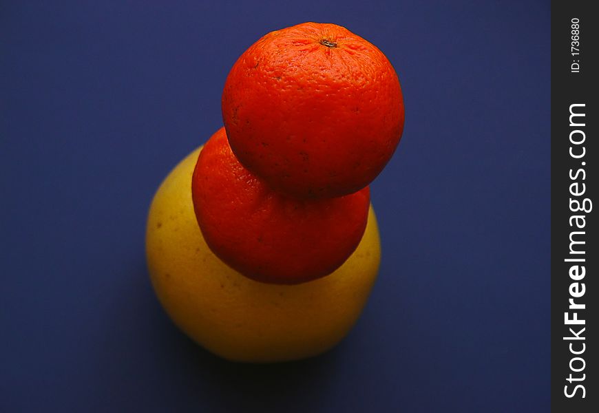 Two oranges stacked atop one yellow grapefruit. Two oranges stacked atop one yellow grapefruit.