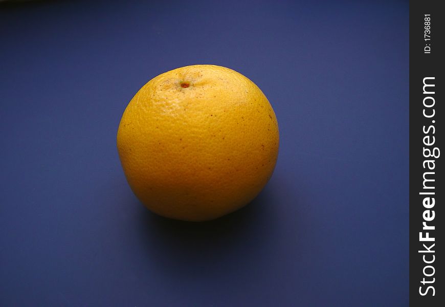 Single Grapefruit on blue background with lighting effects.