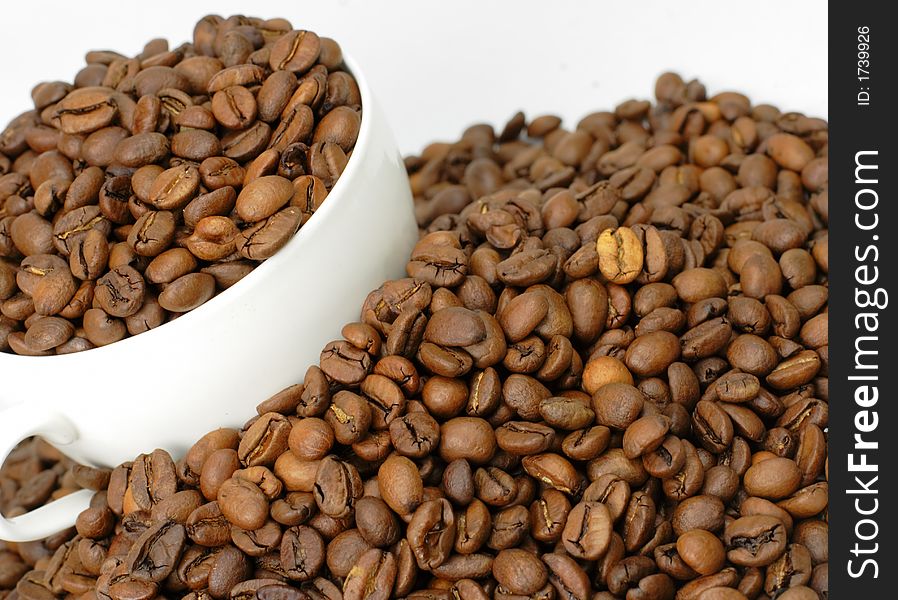 A cup of coffee full with coffee beans in the middle of a heap of coffee beans stacks. A cup of coffee full with coffee beans in the middle of a heap of coffee beans stacks.