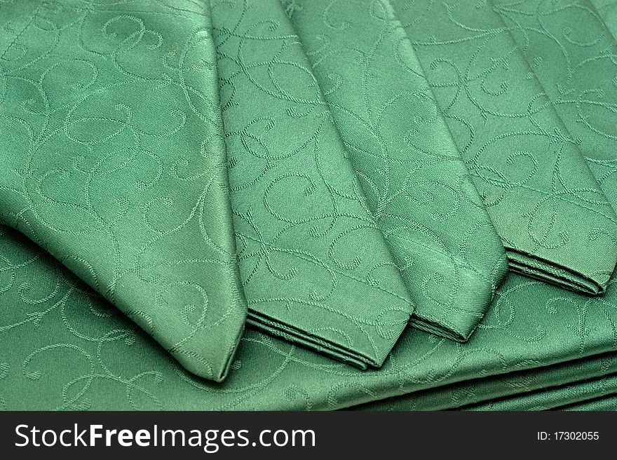 The background of textured green tablecloth and napkin closeup