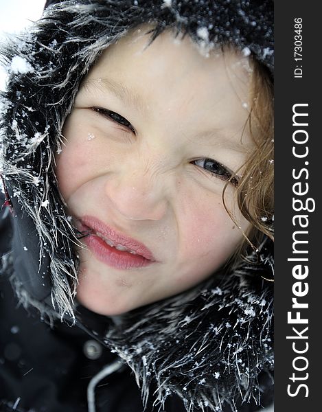 Portrait of a happy young boy outdoors in wintertime wearing a cap full of snow. Portrait of a happy young boy outdoors in wintertime wearing a cap full of snow