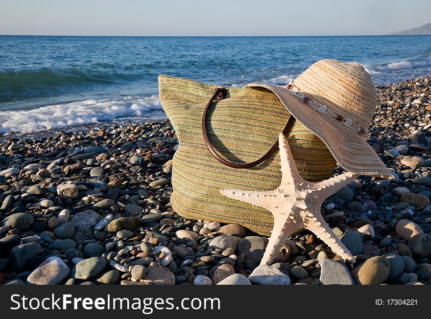 A bonnet, a bag and a seastar are on the coast