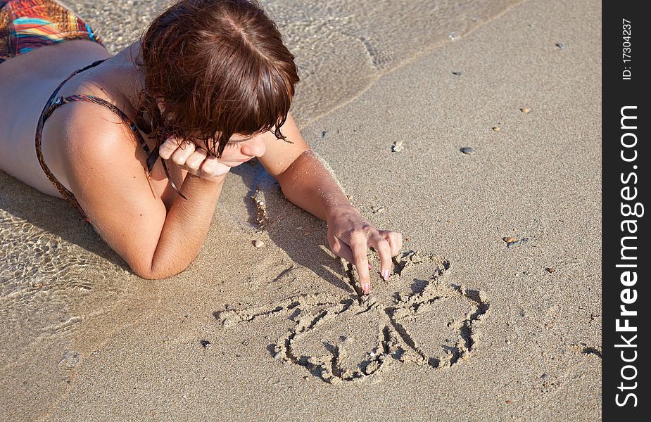 A young girl is painting a clover on a sand