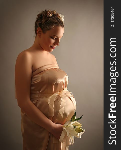 Beautiful pregnant woman wrapped in golden silk. Beautiful pregnant woman wrapped in golden silk