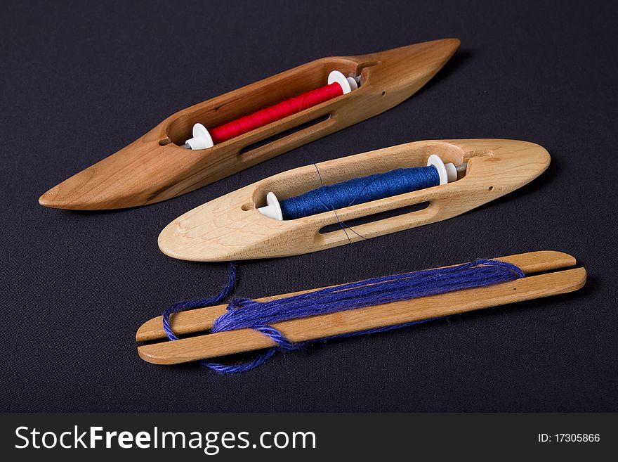 Modern hand weaving tools: shuttles and bobbins, Bobbins are loaded with red and blue threads. Modern hand weaving tools: shuttles and bobbins, Bobbins are loaded with red and blue threads.