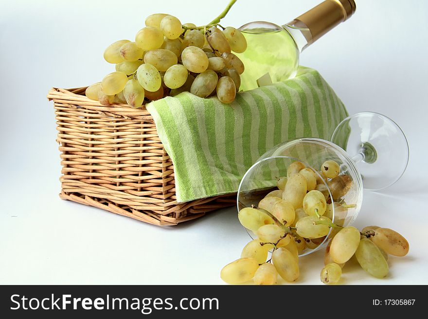 White grapes in a glass and white wine in the basket