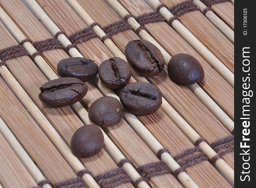 Picture of grains of lying black coffee on the bamboo lining. Picture of grains of lying black coffee on the bamboo lining