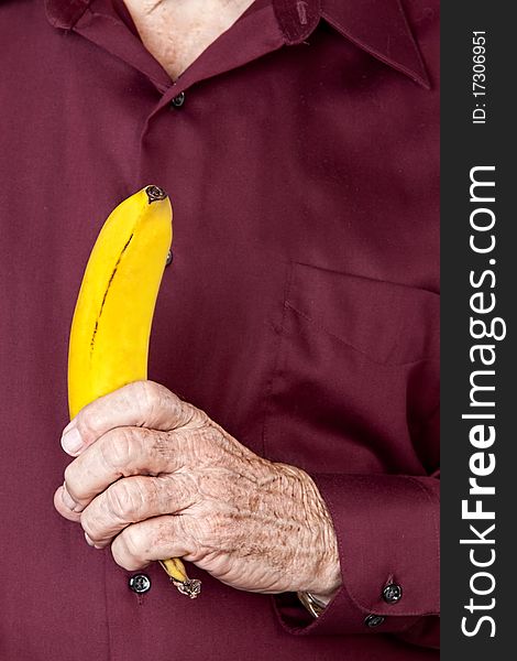 Man wearing maroon shirt holding a ripe banana. Man wearing maroon shirt holding a ripe banana.