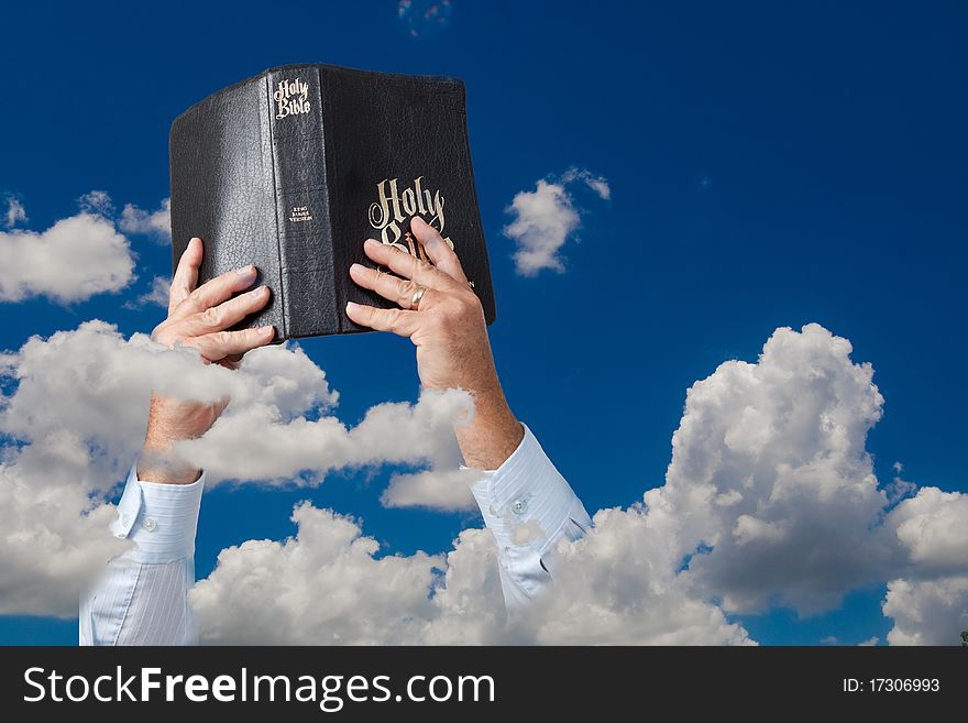 Hands holding up Bible in sky with clouds. Hands holding up Bible in sky with clouds