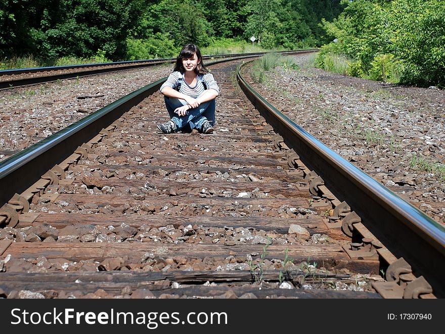 The girl is sitting on the railwayroad