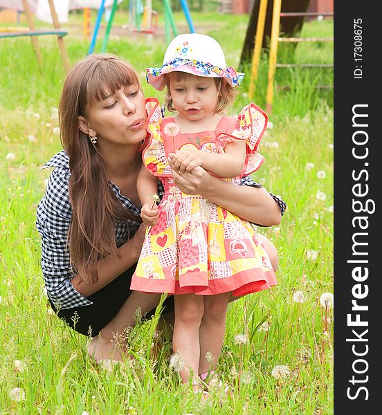 Mum and the daughter blow on a dandelion. Mum and the daughter blow on a dandelion