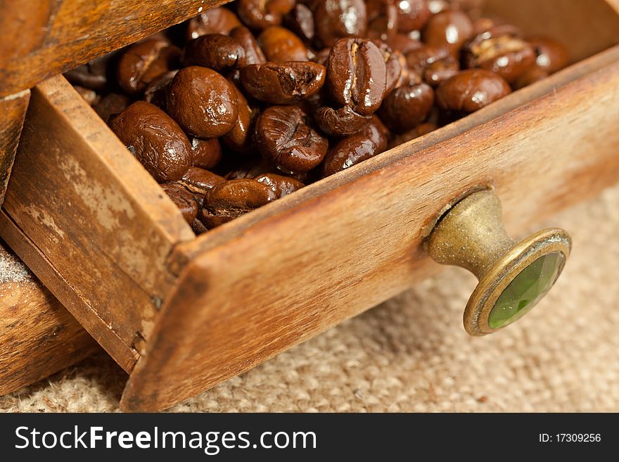 Fragrant fried coffee beans on the wooden coffee grinder