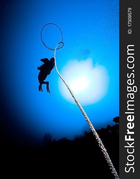 Woman diver's silhouette over the sun