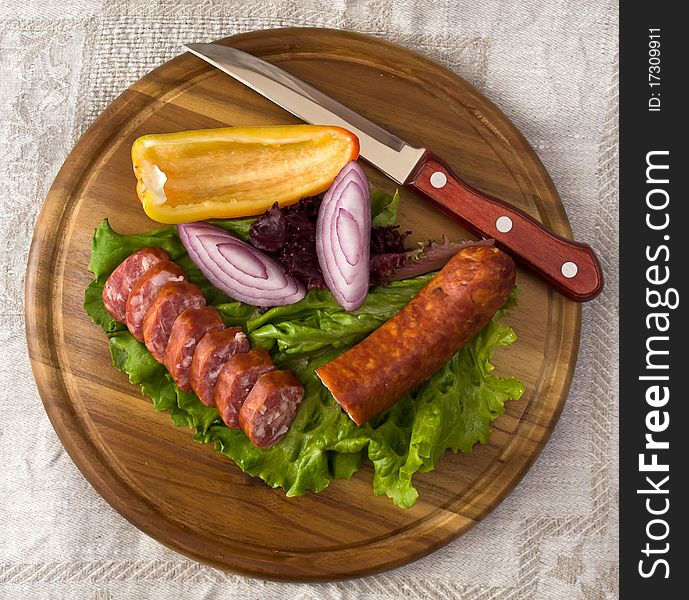 Breakfast close-up. Slices of sausage on the wooden plate with knife