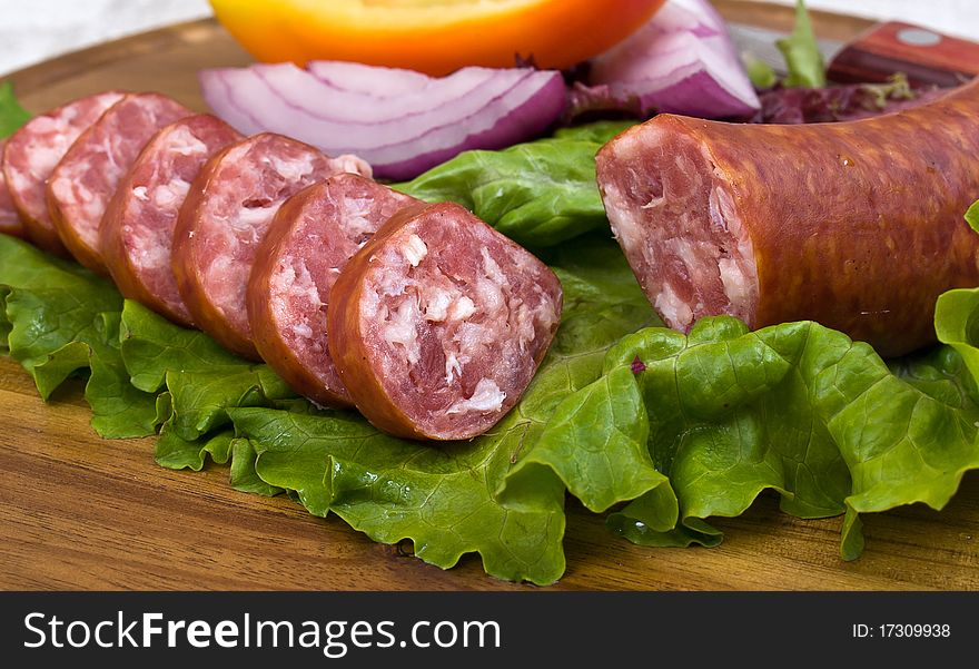 Breakfast close-up. Slices of sausage on the wooden plate with knife