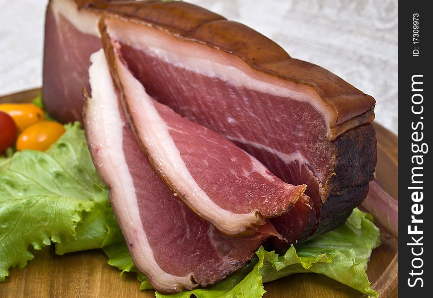 Breakfast close-up. Slices of bacon on the wooden plate with knife