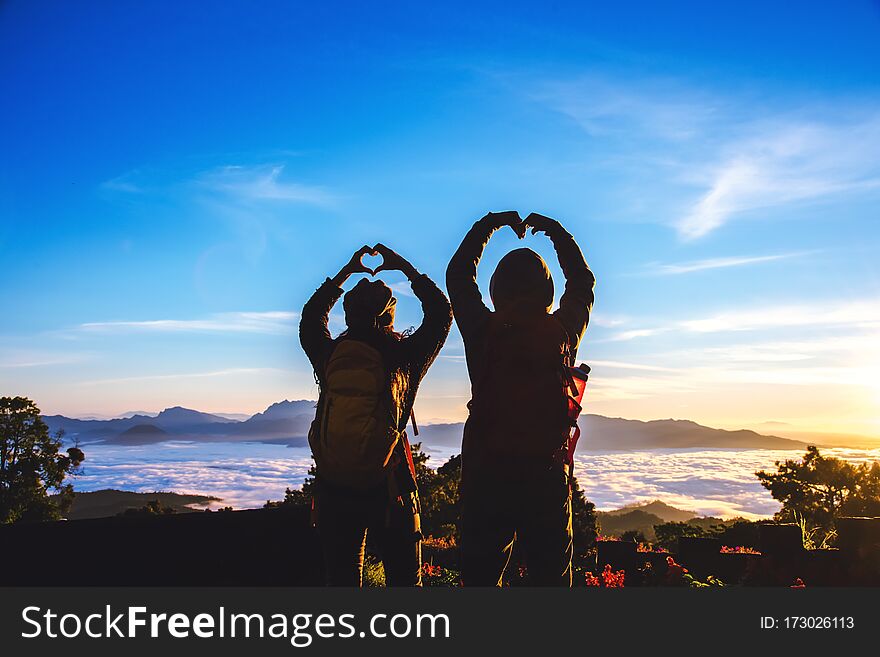 Lover women and men asians travel relax in the holiday. Stand up for sunrise on the Moutain,happy honeymoon,Raised his hand to make a heart shape.