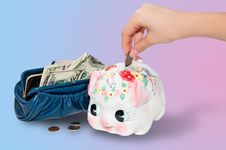 Putting Money Into The Piggy Bank Royalty Free Stock Images